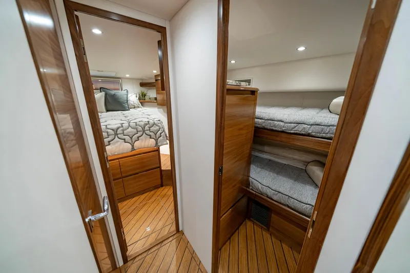 Pamela Yacht Photos Pics 2024 Viking 48 Sport Tower interior with cozy bedroom and bunk beds, featuring elegant wood finishes.