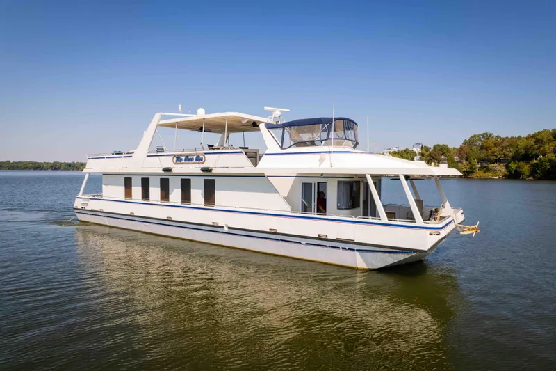  Yacht Photos Pics 2004 Stardust Cruisers houseboat on a calm lake under clear blue skies.