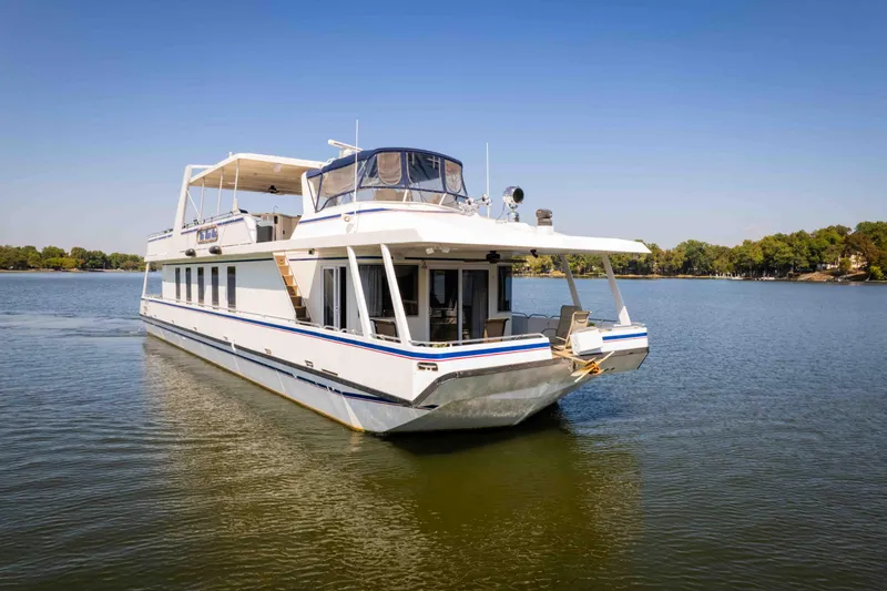  Yacht Photos Pics 2004 Stardust Cruisers houseboat on a serene lake with clear blue skies.