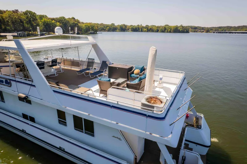  Yacht Photos Pics 2004 Stardust Cruisers houseboat on a serene lake, featuring spacious deck and seating area.