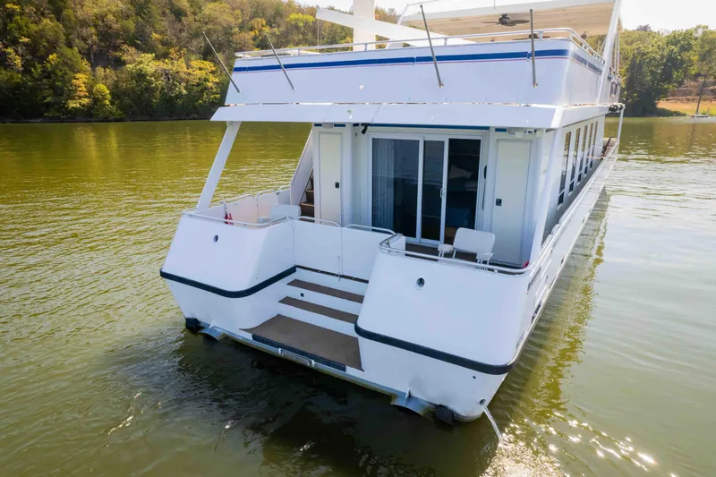  Yacht Photos Pics 2004 Stardust Cruisers houseboat on a serene lake with lush green surroundings.