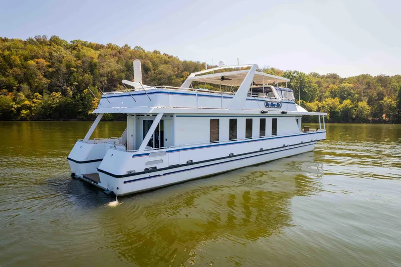  Yacht Photos Pics 2004 Stardust Cruisers houseboat on a serene lake with lush forest backdrop.