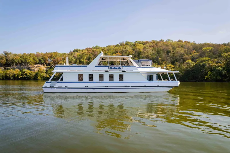  Yacht Photos Pics 2004 Stardust Cruisers houseboat on a serene lake with lush green shoreline.