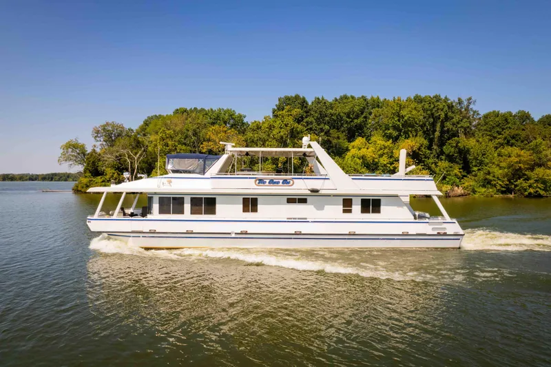  Yacht Photos Pics 2004 Stardust Cruisers houseboat cruising on a serene lake with lush green trees.