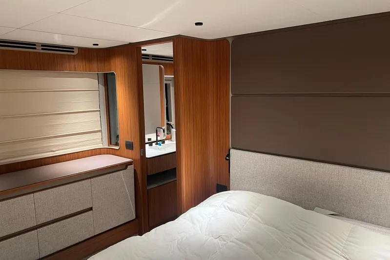  Yacht Photos Pics Luxurious bedroom interior of 2025 Ferretti Yachts 670, featuring modern wood paneling and elegant design.