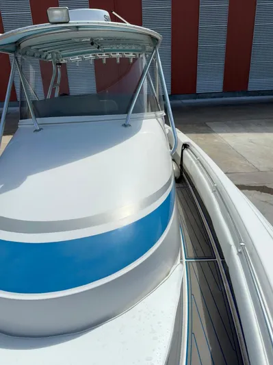  Yacht Photos Pics 2007 Contender 36 Fish Around boat with blue stripe, docked near red and white building.