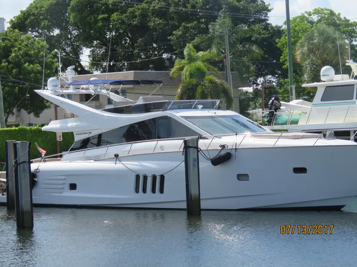  Yacht Photos Pics 2015 Mazarin 72 Sport Fly yacht docked in a marina, surrounded by lush greenery.