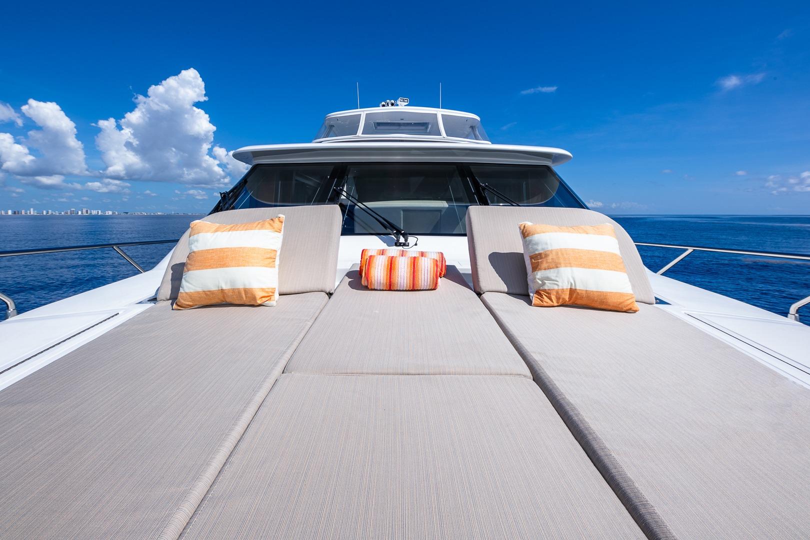 Luxurious 2019 Regency P65 yacht deck with cushions, ocean view, and blue sky.