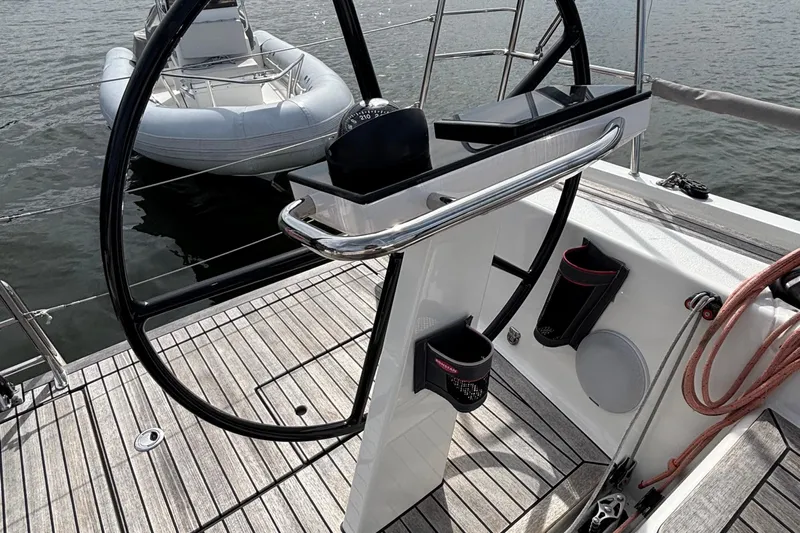 Katara Yacht Photos Pics Steering wheel of 2023 X-Yachts X4³ MkII sailboat with wooden deck and nearby dinghy.