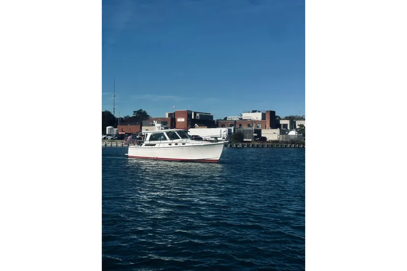 2021 Back Cove 37 Yacht Photos Pics 2021 Back Cove 37 boat cruising on a sunny day near modern waterfront buildings.