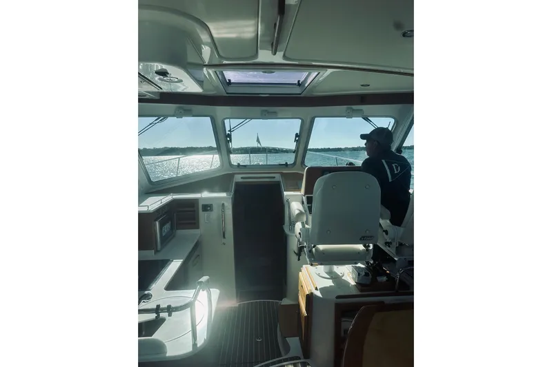 2021 Back Cove 37 Yacht Photos Pics Interior view of 2021 Back Cove 37 boat with person at helm, overlooking water.