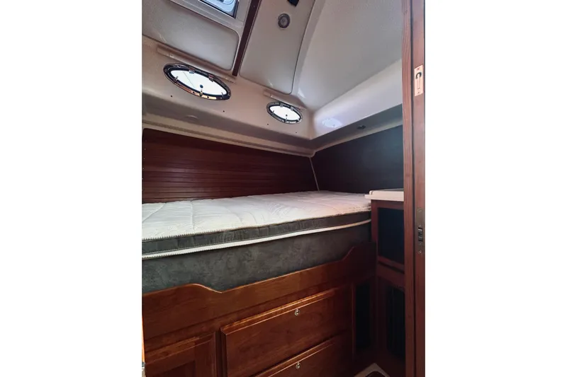 2021 Back Cove 37 Yacht Photos Pics 2021 Back Cove 37 cabin interior with bed, wooden drawers, and portholes.
