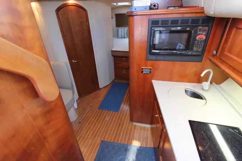 Duke Yacht Photos Pics Interior of a 2005 Rampage 35 Express boat with kitchenette and wooden cabinetry.