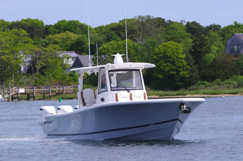 Storm Gray Yacht Photos Pics 2025 Regulator 35 boat cruising on a calm lake with lush green shoreline.