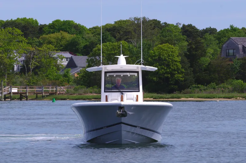 Storm Gray Yacht Photos Pics 2025 Regulator 35 boat cruising on a calm lake with lush green shoreline.