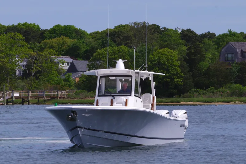 Storm Gray Yacht Photos Pics 2025 Regulator 35 boat cruising on a calm lake near a wooded shoreline.