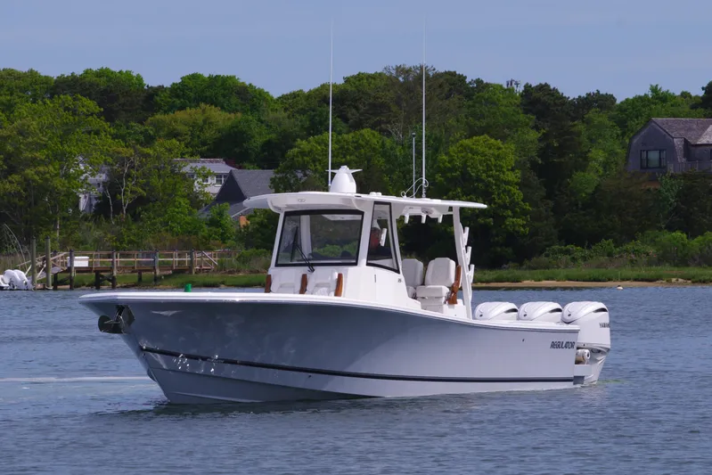 Storm Gray Yacht Photos Pics 2025 Regulator 35 boat cruising on a calm lake with lush green shoreline.