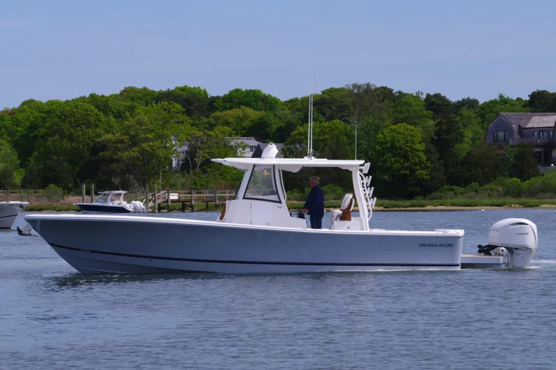 Storm Gray Yacht Photos Pics 2025 Regulator 35 boat cruising on a calm lake with lush green trees in the background.