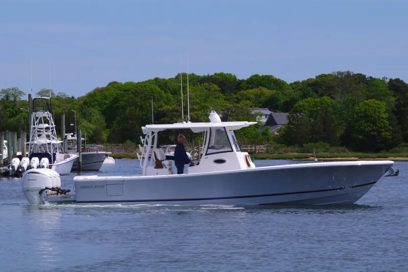 Storm Gray Yacht Photos Pics 2025 Regulator 35 boat cruising on calm water with lush green background.