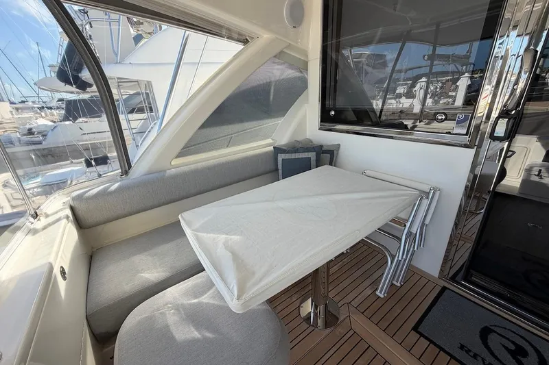  Yacht Photos Pics 2021 Riviera 50 Sports Motor Yacht interior with seating and table, docked at marina.