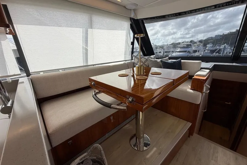  Yacht Photos Pics Interior of 2021 Riviera 50 Sports Motor Yacht with elegant seating and wooden table.