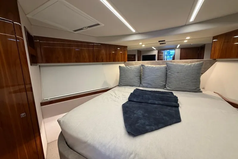  Yacht Photos Pics Luxurious bedroom interior of 2021 Riviera 50 Sports Motor Yacht with elegant wood finishes.