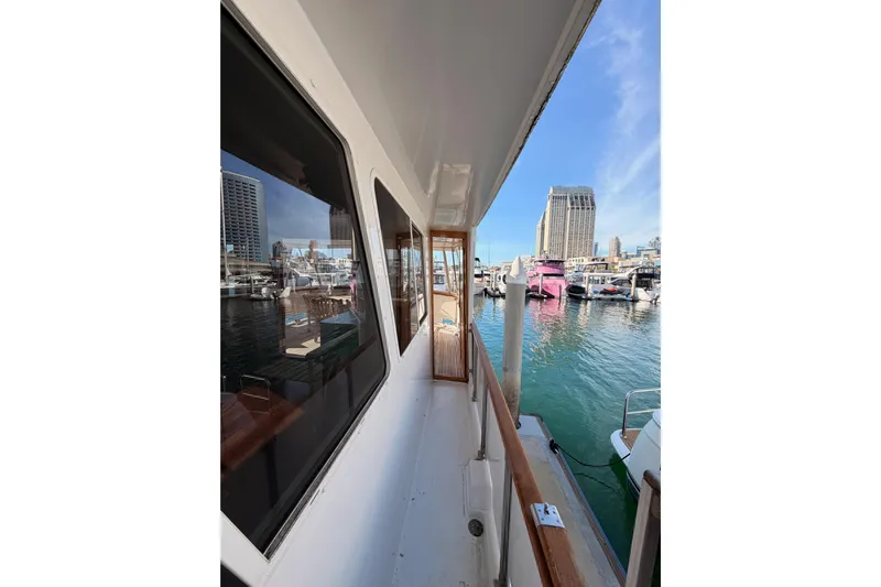 All The Way Yacht Photos Pics 1984 Hartman-Palmer 60 Flush Deck Motor Yacht docked in marina, cityscape background.