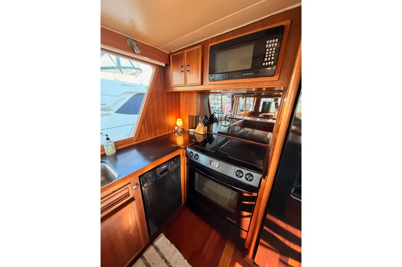 All The Way Yacht Photos Pics 1984 Hartman-Palmer yacht kitchen with wood cabinetry, modern appliances, and window view.