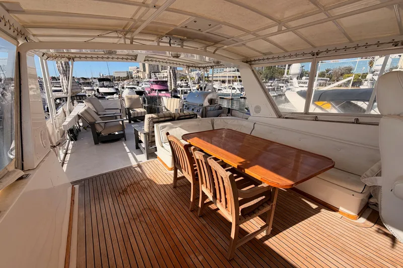 All The Way Yacht Photos Pics 1984 Hartman-Palmer 60 Flush Deck Motor Yacht interior with wooden table and marina view.