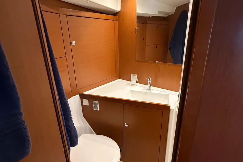 Wildflower III Yacht Photos Pics Bathroom interior of 2016 Beneteau Oceanis 45 yacht, featuring wooden cabinetry and modern sink.