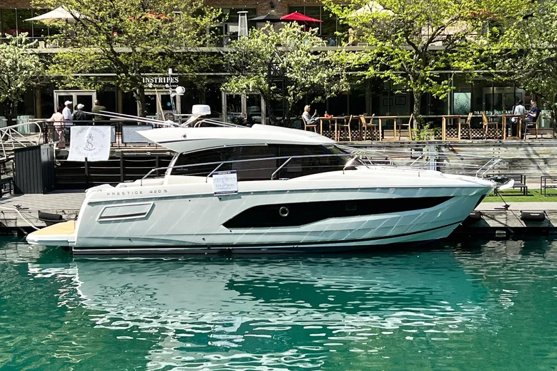  Yacht Photos Pics 2023 Prestige 420S yacht docked by a waterfront restaurant, surrounded by lush greenery.