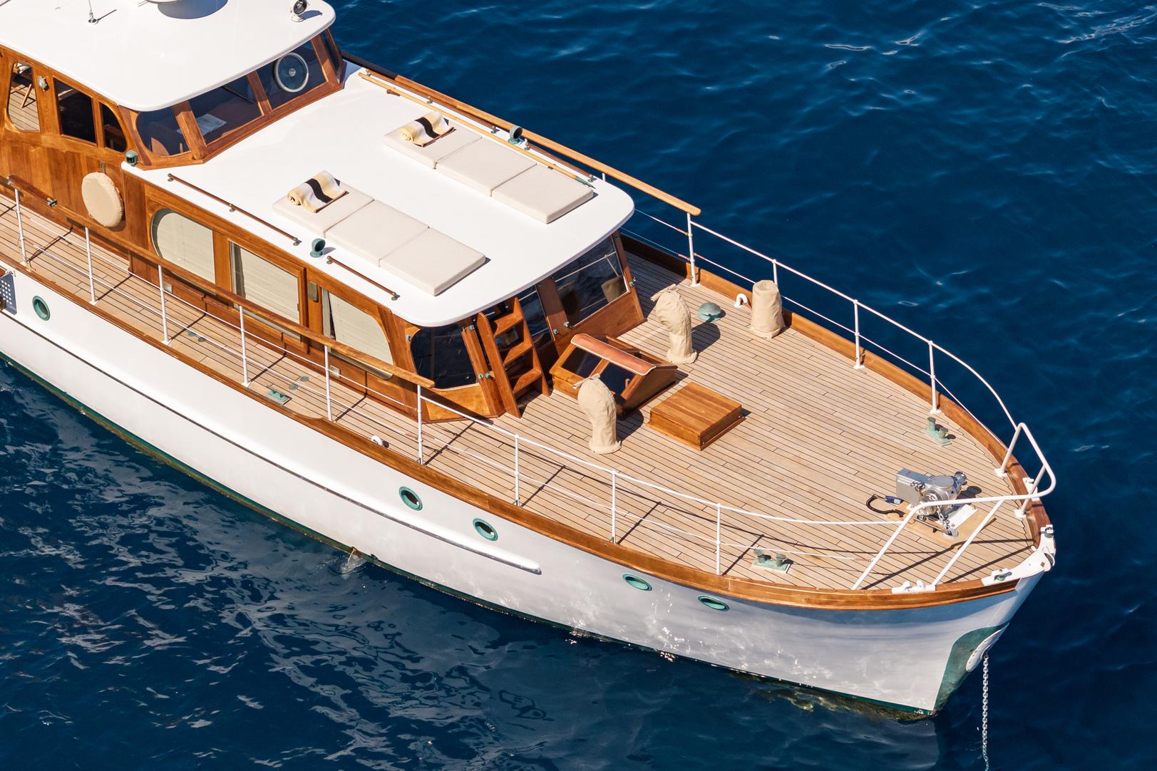 1961 James A Silver yacht with wooden deck on blue water.