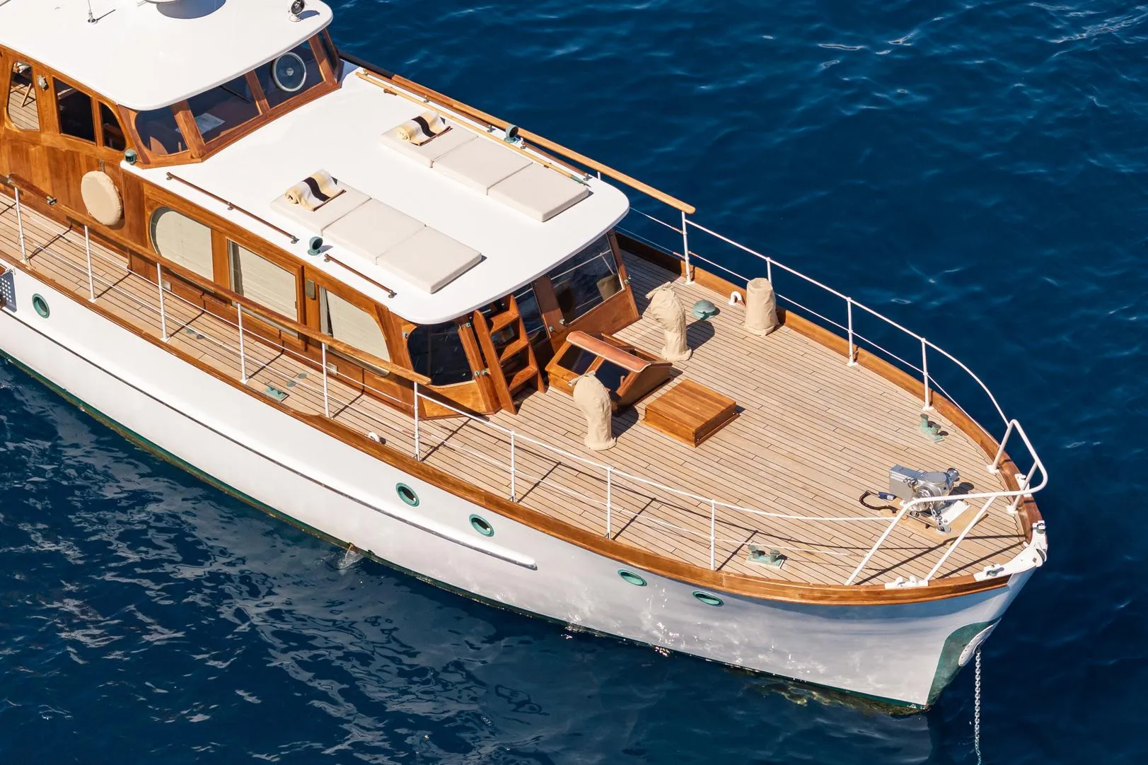 1961 James A Silver yacht with wooden deck on blue water.