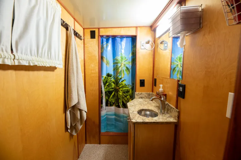 Harborviewbayview Yacht Photos Pics 1993 Custom Steel Trawler bathroom with tropical shower curtain, wooden walls, and granite countertop.