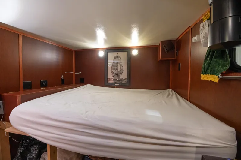 Harborviewbayview Yacht Photos Pics Cozy cabin bedroom in a 1993 Custom Steel Trawler with wooden walls and a framed ship picture.