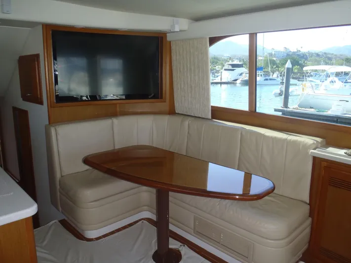 Great White Yacht Photos Pics Interior of 2001 Cabo Flybridge yacht with leather seating and wooden table.