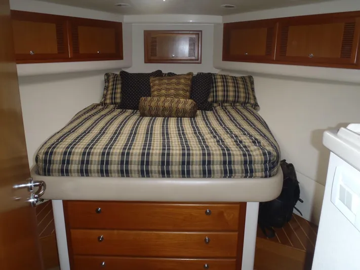 Great White Yacht Photos Pics 2001 Cabo Flybridge cabin with plaid bedding and wooden storage drawers.