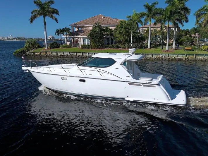 The Adventure Yacht Photos Pics 2008 Tiara Yachts 4300 Sovran cruising on a sunny waterfront with palm trees.