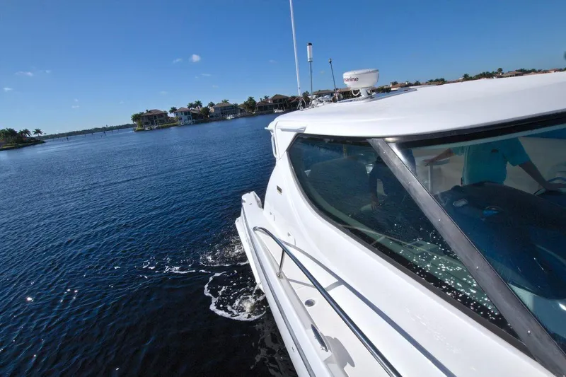 The Adventure Yacht Photos Pics 2008 Tiara Yachts 4300 Sovran cruising on a sunny day, near coastal homes.