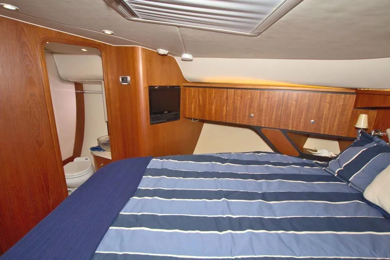 The Adventure Yacht Photos Pics 2008 Tiara Yachts 4300 Sovran cabin with striped bedding and wooden interior.