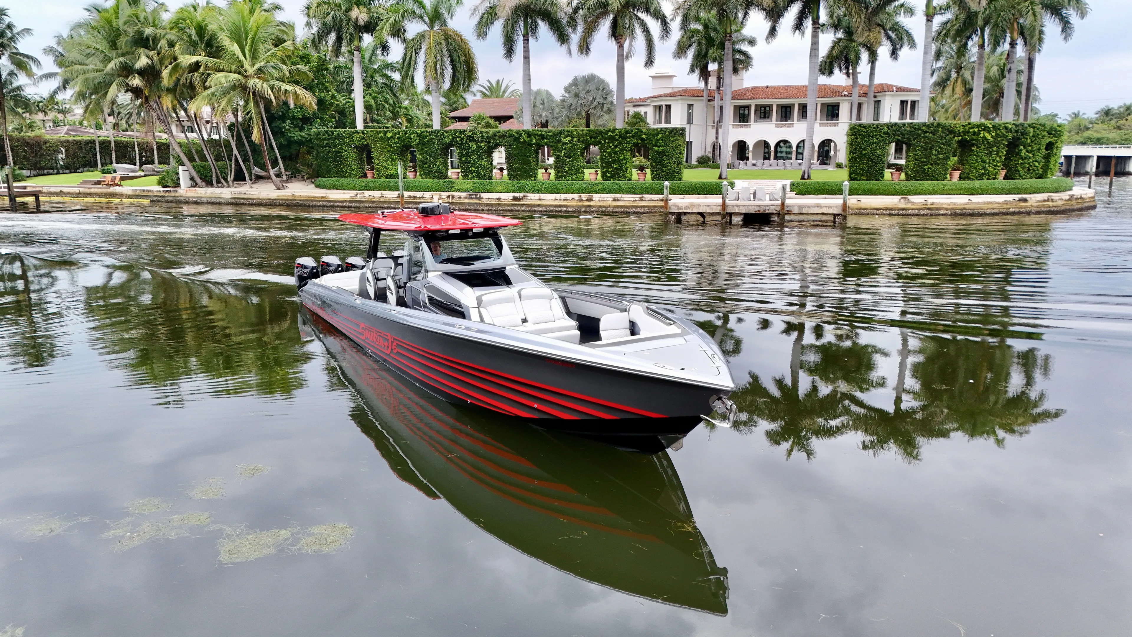  Yacht Photos Pics 2022 Nor-Tech 50 Sport boat cruising near a luxurious waterfront estate with palm trees.