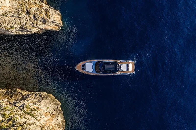  Yacht Photos Pics Aerial view of 2025 Riva Capri 58 yacht navigating between rocky cliffs.