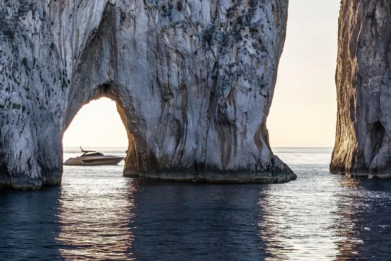  Yacht Photos Pics Riva Capri 58 yacht navigating through rocky archway at sunset, 2025 model.