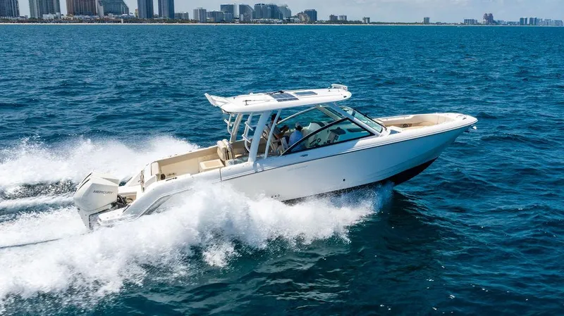  Yacht Photos Pics 2019 Boston Whaler 320 Vantage cruising on open water near a city skyline.