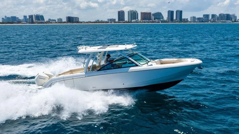  Yacht Photos Pics 2019 Boston Whaler 320 Vantage cruising on ocean with city skyline in background.