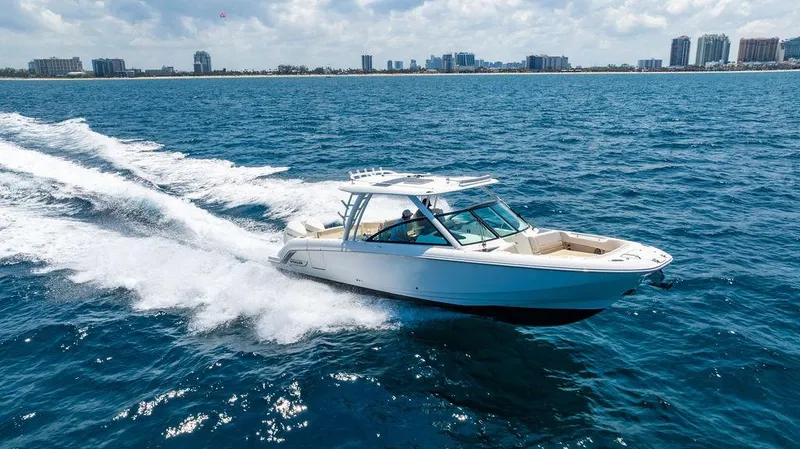  Yacht Photos Pics 2019 Boston Whaler 320 Vantage cruising on open water with city skyline in background.