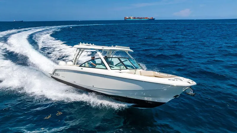  Yacht Photos Pics 2019 Boston Whaler 320 Vantage cruising on open sea with cargo ship in background.