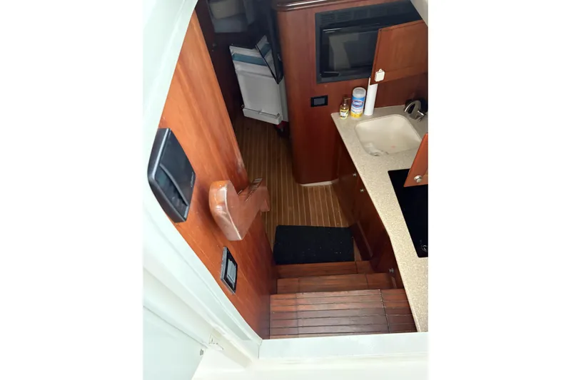  Yacht Photos Pics Interior view of 2006 Rampage 38 Express boat, featuring wooden stairs and compact kitchen area.