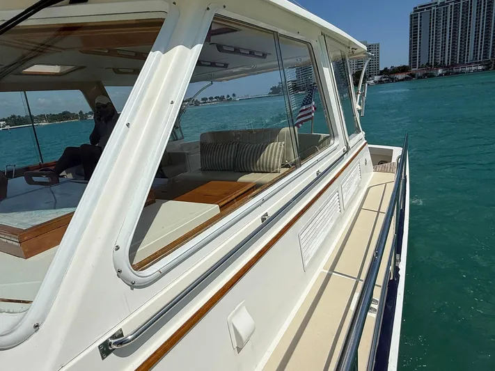 Fiji Yacht Photos Pics 1999 Grand Banks 49 Eastbay HX yacht cruising on turquoise waters near a cityscape.