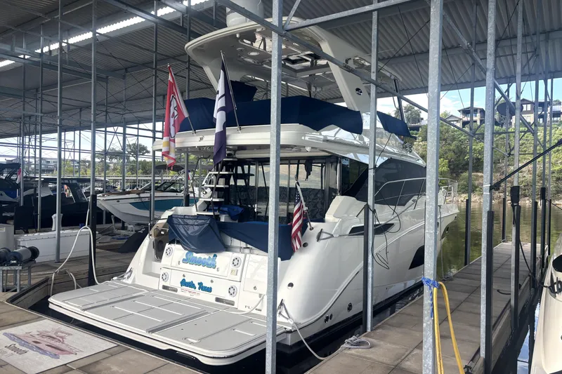 Smooth Yacht Photos Pics 2018 Sea Ray Fly 460 yacht docked in a covered marina, flags displayed.